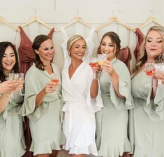 a group of women standing next to each other holding wine glasses