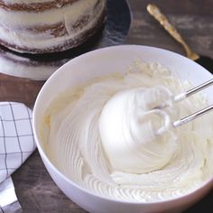 a white bowl filled with frosting next to a cake