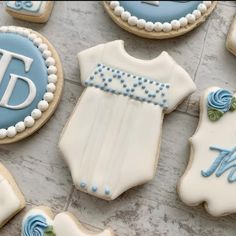 cookies decorated with blue and white icing are arranged on a tablecloth that says it's a boy