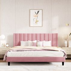 a pink bed with white sheets and pillows in front of a painting on the wall