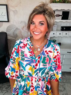 Flirty and feminine, the Wild Flowers blouse blooms with carefree charm. Delicate babydoll styling and a breezy v-neckline cultivate an effortless bohemian elegance, while optional front ties allow you to tailor the fit to your whimsy. Whether you leave the ties undone for a billowy silhouette or cinch them for a more structured shape, this top's floral print in a soft, lightweight material exudes a wanderlust spirit. 3/4 balloon sleeves with sweet piping details round out the dreamy details of Bohemian V-neck Peasant Top With Floral Print, Feminine V-neck Peasant Top For Brunch, Multicolor Floral Print V-neck Peasant Top, Vacation Floral Print Blouse With Split Neck, Summer Feminine V-neck Peasant Top, Feminine Summer Peasant Top With V-neck, Feminine Summer Peasant Top V-neck, Spring Flowy Blouse With Split Neck, Vacation Split Neck Blouse With Floral Print