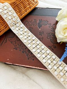 a bouquet of flowers sitting on top of a book next to a basket with pearls