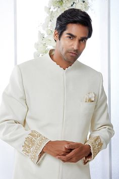 This ivory sherwani set features kiran dori embroidery on the cuffs and a stepper collar detail on a matka silk base. This ensemble is paired with a cotton silk kurta and a stretchable cotton silk trouser. Complimenting footwear is also available.From Seema Gujral's Tuscan Summer collection. DELIVERY TIMEPlease allow 8-12 weeks for your outfit to arrive.FABRIC DETAILSMatka SilkProfessional cleaning only. Off White Naqshi Bandhgala For Festive Occasions, Off White Bandhgala With Naqshi For Festive Occasions, Eid Fitted Kurta With Embroidered Cuffs, Cream Sherwani With Chikankari Embroidery And Long Sleeves, Cream Long Sleeve Sherwani With Chikankari Embroidery, Festive Off White Bandhgala With Naqshi, Off White Bandhgala With Naqshi For Diwali, Off White Naqshi Bandhgala For Diwali, Fitted Sets With Embroidered Cuffs For Festive Occasions