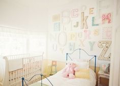 a child's bedroom with letters on the wall and a teddy bear at the foot of the bed