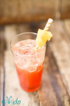 a close up of a drink on a table with a pineapple garnish