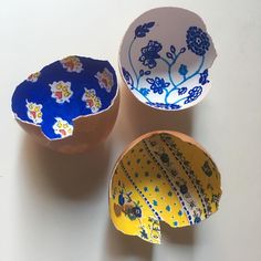 three bowls sitting on top of a white table next to each other, one with blue and yellow designs