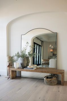 a mirror sitting on top of a wooden table next to a vase filled with flowers