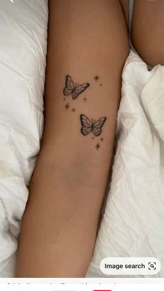 a woman's arm with two butterflies on it and stars in the sky above her