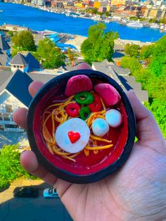 a hand holding a small bowl filled with candy and candies on top of a roof