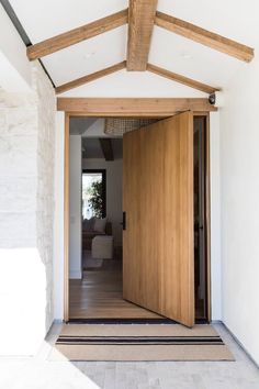 an open door leading to a living room with a couch in the corner and wood beams on the ceiling