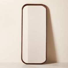 a mirror on the wall with a wooden frame around it's edge, against a white background