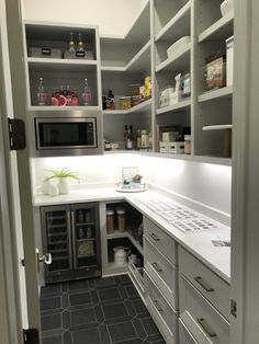 a kitchen with gray cabinets and white counter tops, black tile flooring and open shelving