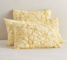 two yellow pillows sitting next to each other on a bed