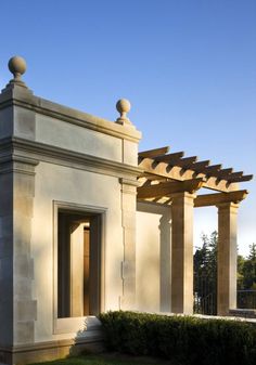 an old building with pillars and arches in the front yard, on a sunny day