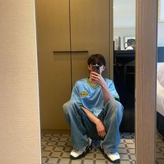 a man sitting on the floor taking a selfie in front of a bathroom mirror