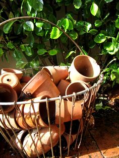 a basket full of clay pots sitting on the ground