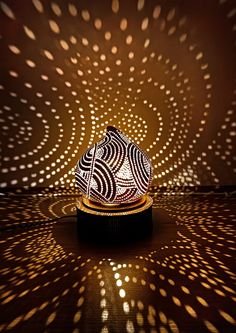 an intricately designed hat sits on a stand in front of a wall with lights