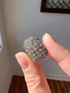 a woman's hand is holding an old diamond ring in front of her face