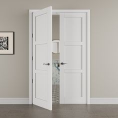 an open white door in a room with wood flooring and wall art on the walls