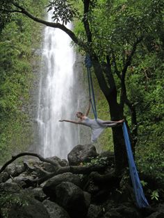 a man is hanging from a rope in front of a waterfall