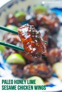 a close up of food on a stick with chopsticks in the foreground and text overlay reading paleo honey lime sesame chicken wings