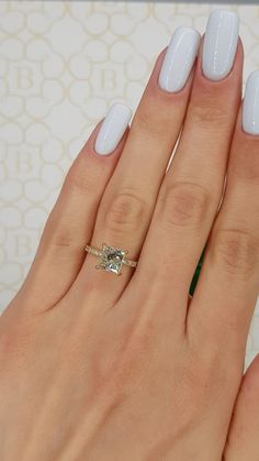 a woman's hand with white manicured nails and a ring on her finger