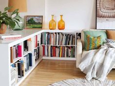 a living room filled with lots of books next to a white book shelf full of books