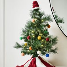 a small christmas tree in a red and white cloth bag with lights on the top