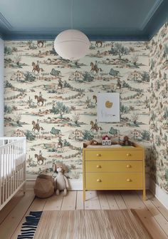 a baby's room with a yellow dresser and wallpaper