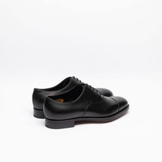 Black calf oxford shoe with stitched cap toe, double leather sole. Fitting F, last 202. Made in England Timeless Oxford Shoes For Business, Leather Oxfords With Leather Sole For Derby, Classic Oxford Lace-up Shoes With Rubber Heel Cap, Fitted Goodyear Welted Cap Toe Derby, Timeless Leather Sole Oxfords, Goodyear Welted Almond Toe Oxfords, Classic Goodyear Welted Lace-up Shoes With Almond Toe, Classic Lace-up Shoes With Goodyear Welted Almond Toe, Classic Lace-up Shoes With Goodyear Welt And Almond Toe