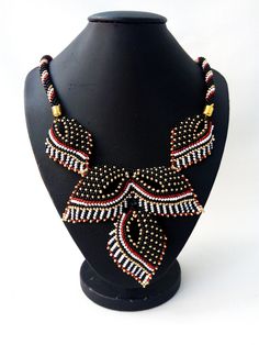 "Original beautiful beaded necklace in black and red gold. Beadwork. The modern design of the necklace will emphasize your individuality and originality, beads will complement any look. This necklace made of delicate leaves suits any outfit. Jewelry for women. An unusual gift for a friend. The size of the necklace is 45 cm (17.71 \"). Three Leaf Pendant Length 9 cm (3.54 \") If you have any questions for me, please contact me. Thanks for watching and interest in my work." Adjustable Black Necklace With Gold Beads, Traditional Red Necklaces With Black Beads, Traditional Red Necklace With Black Beads, Black Beaded Chain Beads As Gift, Black Beaded Chain For Gift, Black Beaded Necklace With Gold Beads As Gift, Black Beaded Chain As A Gift, Black Beaded Choker As Gift, Black Necklaces With Round Gold Beads