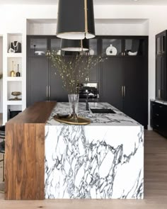 a kitchen with marble counter tops and black cabinets in the back drop off cabinetry