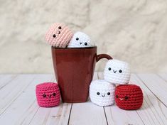 small crocheted marshmallows sitting next to a coffee cup