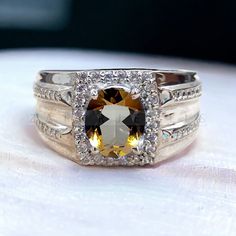 a ring with an orange and white stone surrounded by diamonds on top of a table