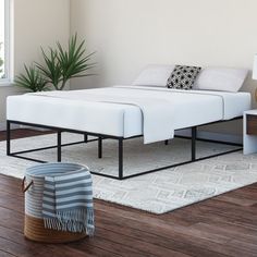 a bed sitting on top of a wooden floor next to a white rug and window