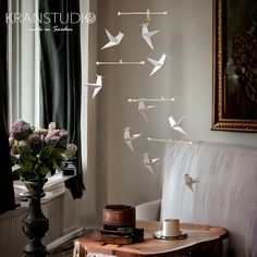 a living room with a white couch and some birds on the wall hanging from it