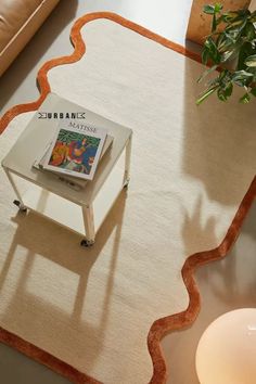 a table with a magazine on it in front of a couch and potted plant