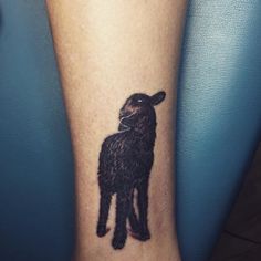 a small black sheep tattoo on the leg