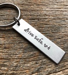 a metal keychain with the words alive safe on it sitting on a wooden surface