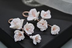 four white flowers are sitting on top of a black box with pearls in the middle