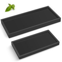 two black trays with green leaves on them