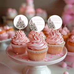 cupcakes with pink frosting and trees on top are sitting on a cake plate