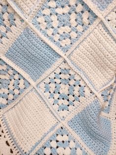 a blue and white crocheted blanket laying on top of a table