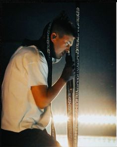 a man with dreadlocks on his head is leaning against a pole in the dark