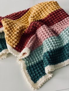 three crocheted blankets are laying on the floor together, one is multicolored