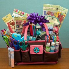 a pink and brown purse filled with lots of crafting supplies on top of a wooden table