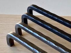 three metal objects sitting on top of a wooden table next to each other and one is black