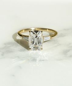 an engagement ring with two baguets on the side and a diamond in the middle