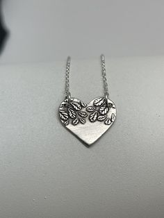 This unique Modern Silver Heart Tree Necklace is handmade using .950 sterling silver. It has been cut from sterling silver precious metal clay, textured, fired and oxidized. The pendant hangs from a sterling silver diamond cut cable chain. From the Modern Tree Collection, this fine silver pendant features an embossed modern boho leaf print pattern and hangs 5/8 inch from top of ring to bottom of the hexagon shape. Pendant size: approximately 1/2 x 5/8 inches Chain length: adjustable at 16 and 18 Heart-shaped Sterling Silver Soldered Necklace, Sterling Silver Heart-shaped Soldered Necklaces, Sterling Silver Heart-shaped Soldered Necklace, Sterling Silver Heart Necklace With Soldered Details, Artisan Silver Heart Pendant Necklace, Stamped Sterling Silver Heart Pendant Necklace, Unique Silver Heart Necklace For Gift, Unique Hand Forged Heart-shaped Jewelry, Handmade Silver Heart Necklace For Mom