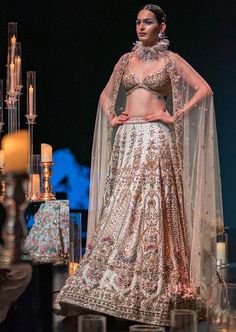 This enchanting earthy beige lehenga set is a beautiful blend of exuberance and grandeur. An ensemble that you will want this wedding season includes a lehenga, a blouse, a dupatta and a veil. Stitched to perfection, the lehenga features 3D embroideries with organza flowers using pearls, salli, cutdana, and stud tassels. The sleeveless blouse features a scintillating sweetheart neckline with handcrafted finish and a back hook closure. Paired with a heavy net dupatta, the cut-work detailing and intricate embroidery take center-stage. The lehenga comes with an attached cancan and the blouse has padding. Completed with a veil, this opulent ensemble silhouette will glimmer in the spotlight. Dry-clean only if required. Slight variation in color is possible due to digital photography. Floor-length Lehenga With Intricate Embroidery For Wedding Reception, Festive Floor-length Gown For Wedding Reception, Anarkali Floor-length Gown For Wedding Reception, Floor-length Embroidered Gown For Wedding Reception, Intricate Embroidery Floor-length Gown For Wedding Reception, Floor-length Gown With Intricate Embroidery For Wedding Reception, Elegant Lehenga With Intricate Embroidery For Wedding Reception, Festive Resham Embroidered Lehenga For Wedding Reception, Festive Resham Embroidery Lehenga For Wedding Reception